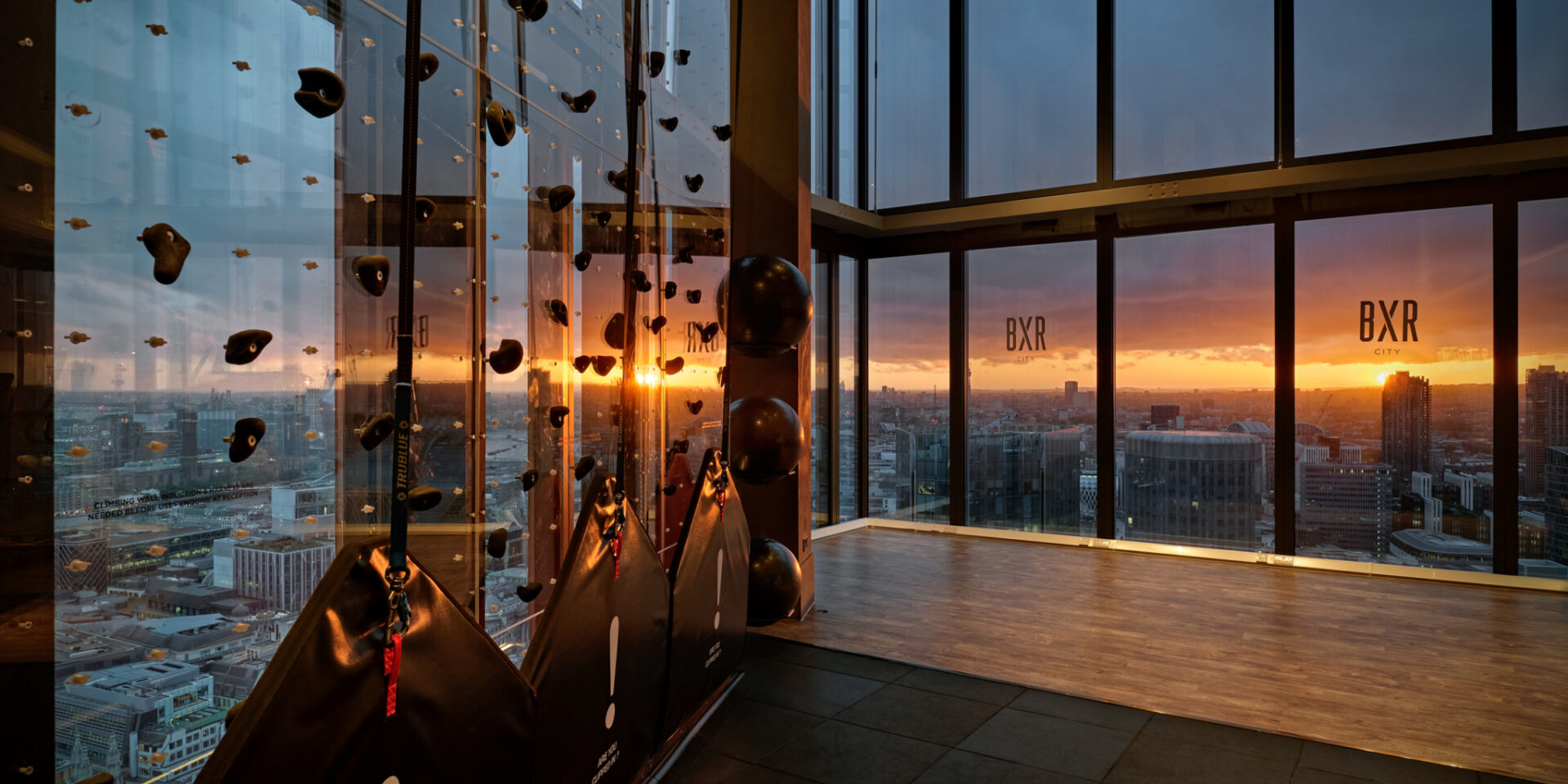 BXR City training space with a climbing wall and sunset city view