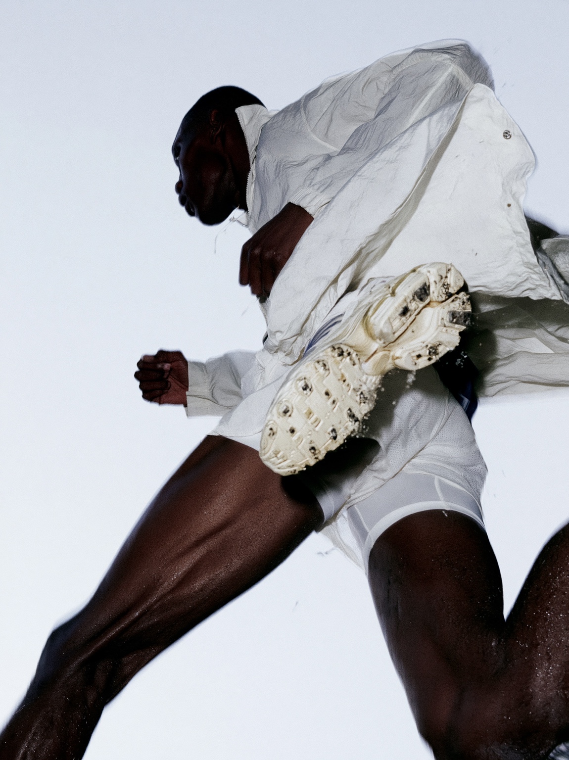 Athlete in white captured in motion against a pale studio background